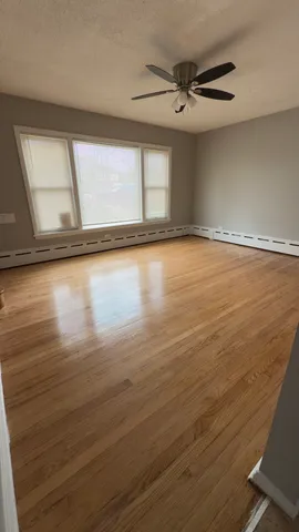 a view of an empty room with a window and wooden floor