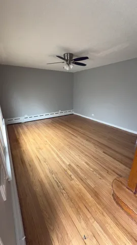 a view of empty room with wooden floor and window