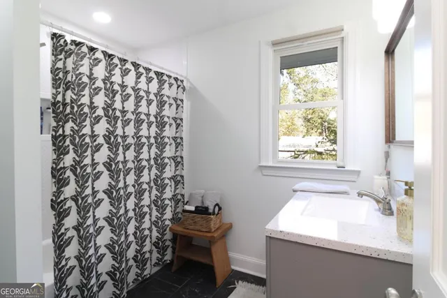 a bathroom with a sink toilet and next to a window