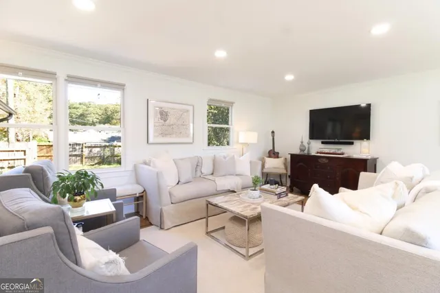 a living room with furniture a flat screen tv and a large window