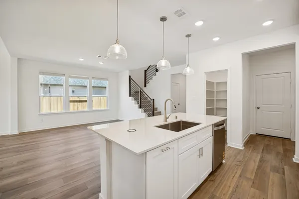 a large kitchen with kitchen island a stove a sink a center island and wooden floor