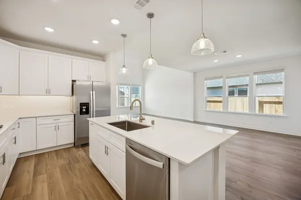 a kitchen that has a lot of white cabinets and stainless steel appliances