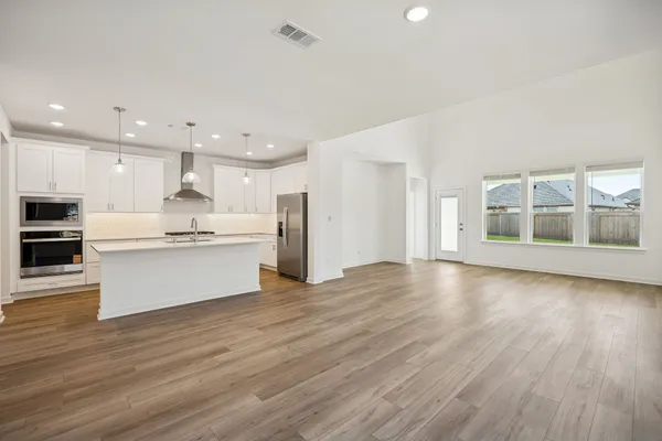 a view of kitchen with kitchen island wooden floors and stainless steel appliances