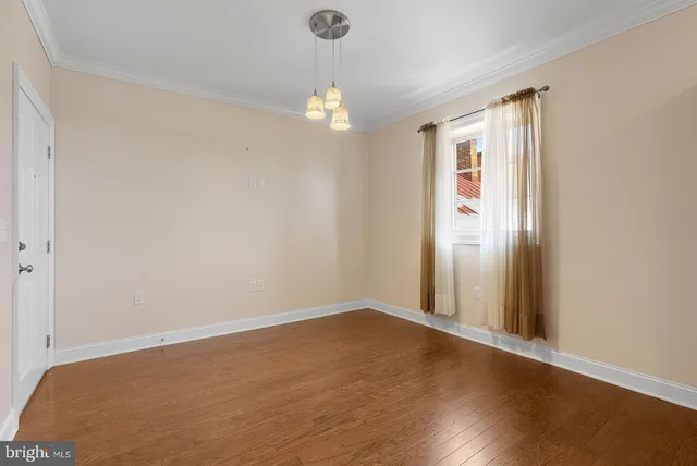 an empty room with wooden floor and chandelier