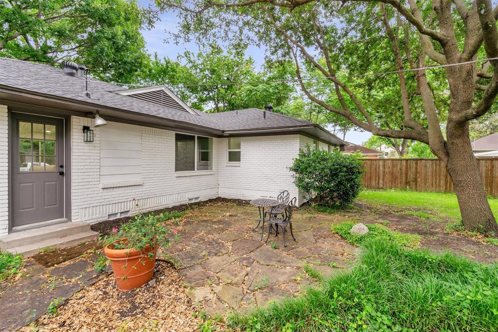 4815 Kelman Street Dallas, TX 75214 - Photo 35 of 37 Spacious backyard featuring a stone patio, mature trees, and a wooden privacy fence