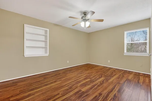 a view of an empty room with wooden floor and a window