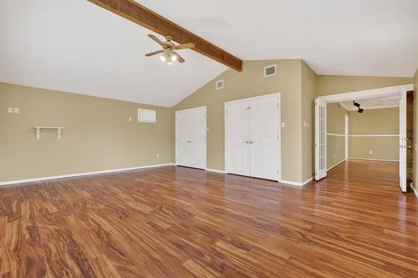 a view of an empty room with wooden floor and a window