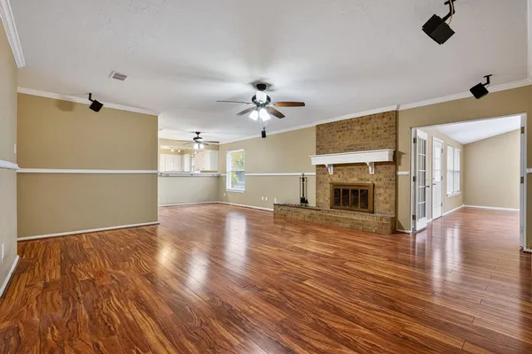 a view of a livingroom with a fireplace a ceiling fan and wooden floor