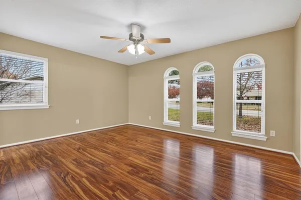 a view of an empty room with wooden floor and window