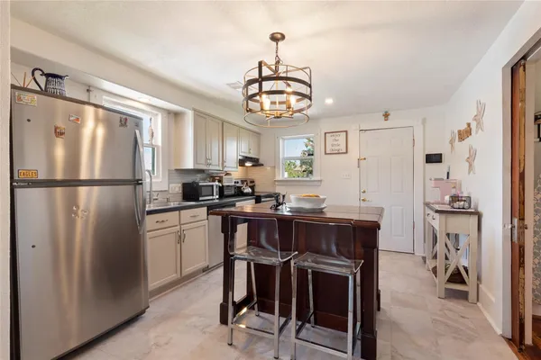 a kitchen with stainless steel appliances granite countertop a refrigerator a sink dishwasher a stove a dining table and chairs with wooden floor