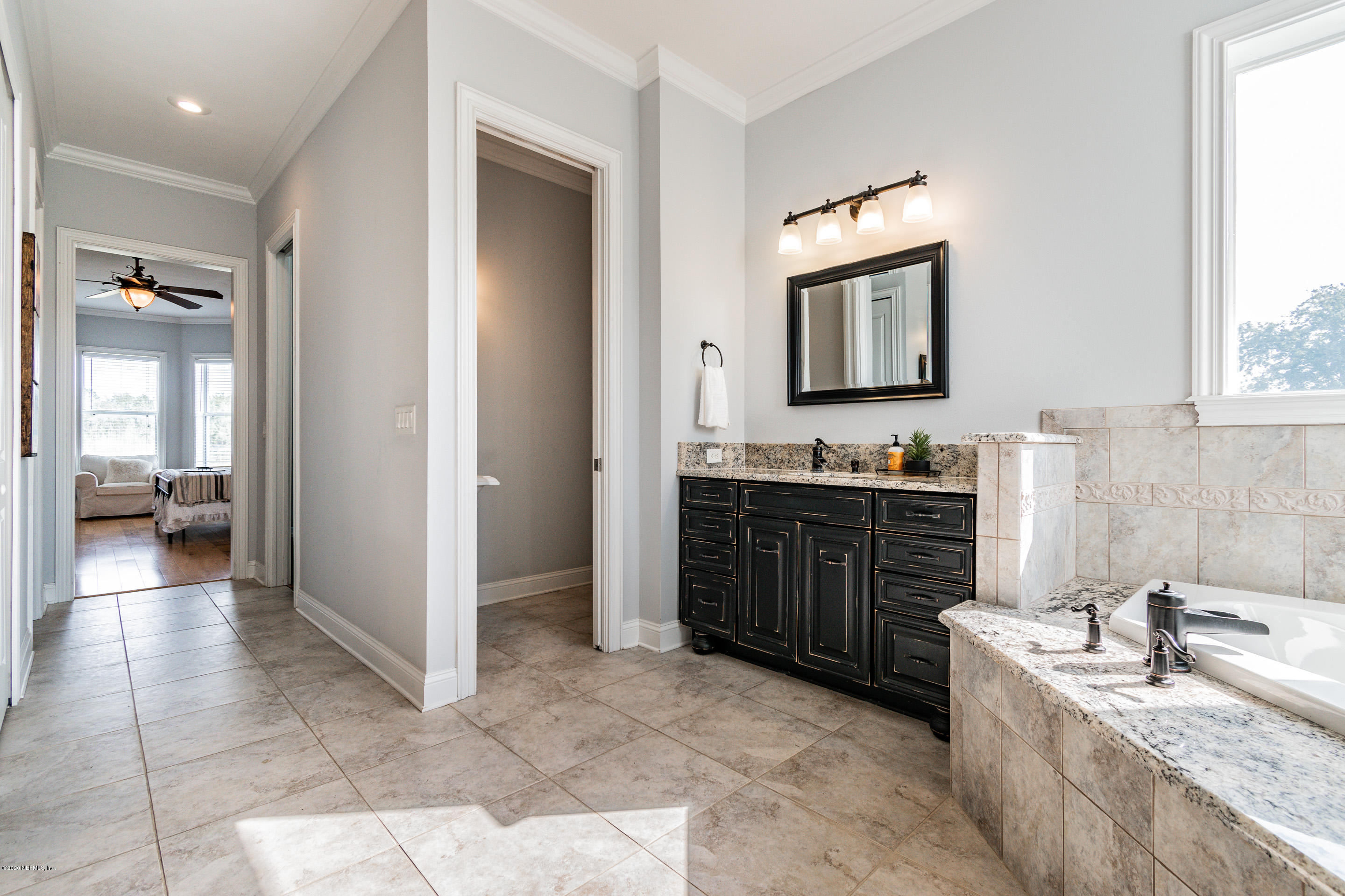 14689 Diamond Ranch Drive Jacksonville, FL 32234 - Photo 38 of 76 a large bathroom with a granite countertop double vanity sink a mirror and a bathtub