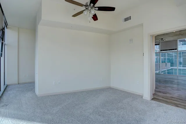 an empty room with wooden floor fan and windows