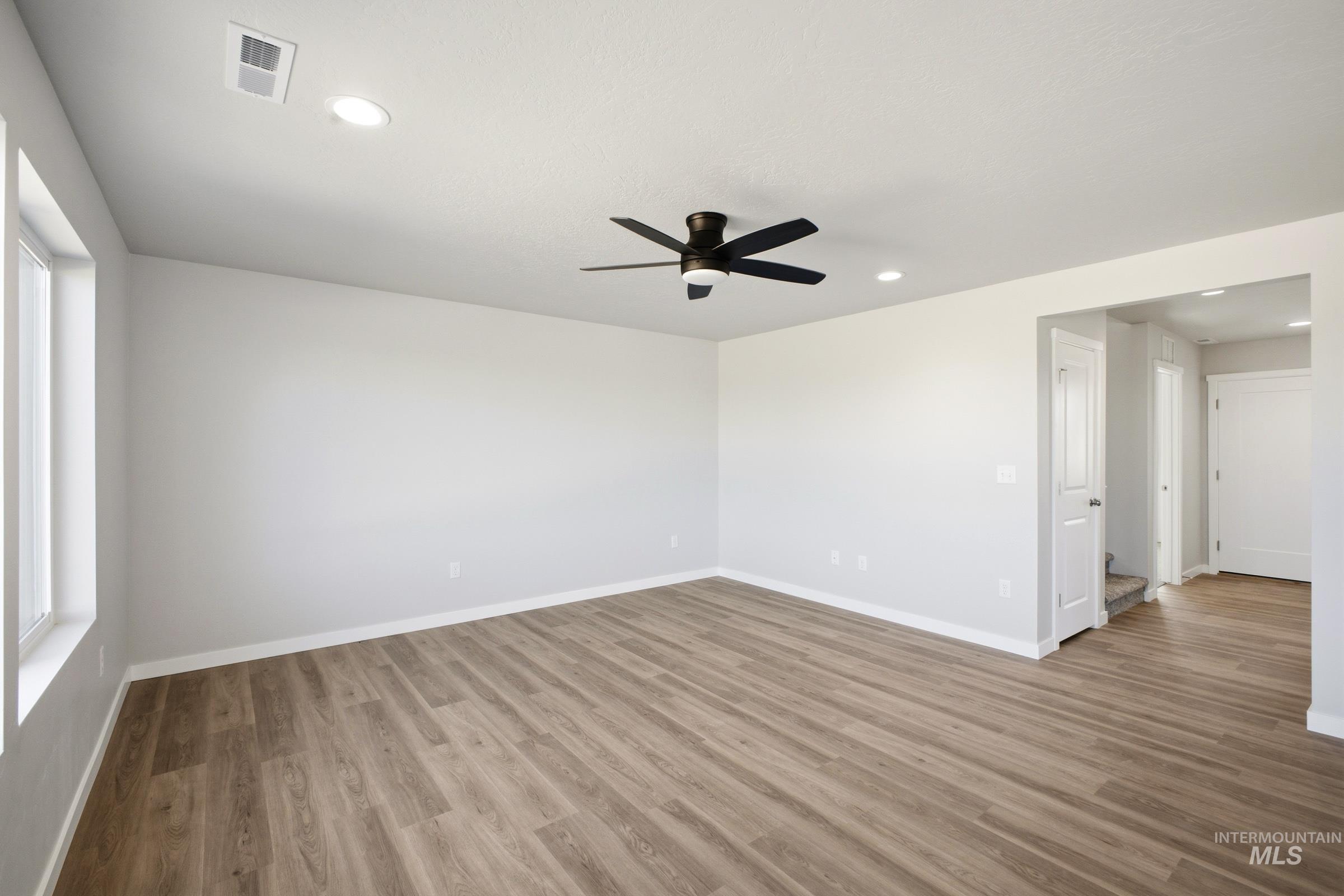 13325 Scrape Street Caldwell, ID 83607 - Photo 8 of 24 Spacious room featuring wood-finish flooring, white walls, multiple windows, a ceiling fan, and recessed lighting
