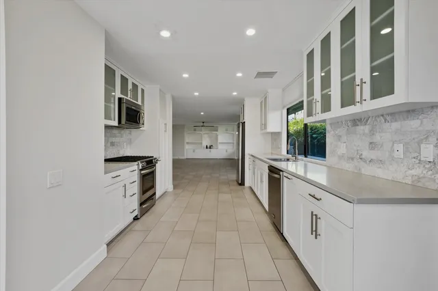a large kitchen with stainless steel appliances a sink and cabinets