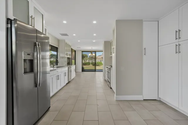 a large white kitchen with a sink and refrigerator