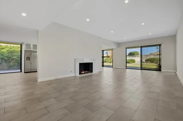 an empty room with floor to ceiling windows and fireplace