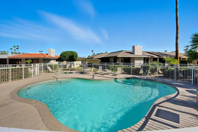 a view of a swimming pool with lawn chairs and plants