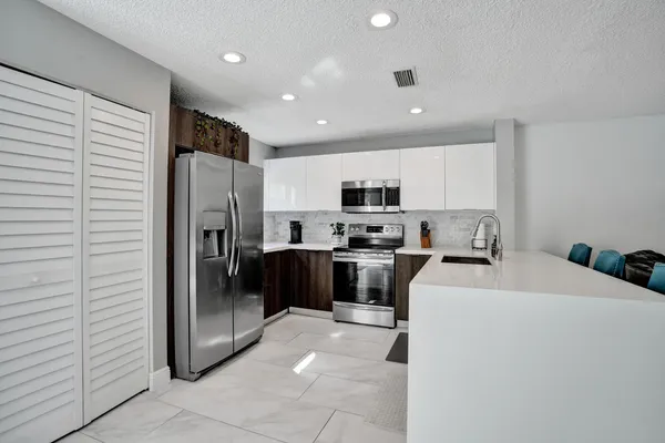 a kitchen with stainless steel appliances a microwave sink refrigerator and cabinets
