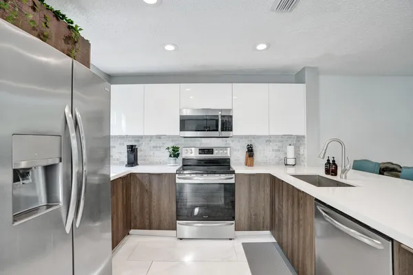 a kitchen with stainless steel appliances granite countertop a refrigerator a stove and a sink with wooden floor