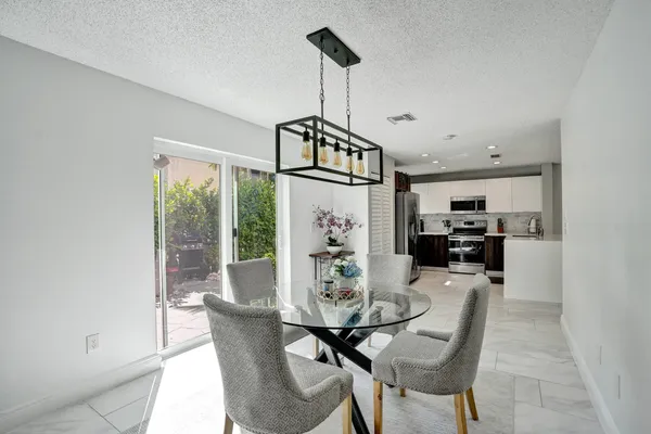 a kitchen with kitchen island a dining table chairs cabinets and a sink