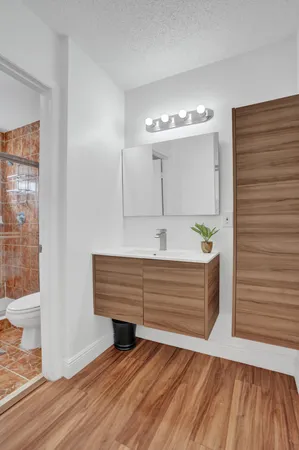 a bedroom with a bed potted plant on dresser and a wooden floor