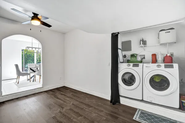 a wooden bench sitting in backside of a house with potted plants and a bench
