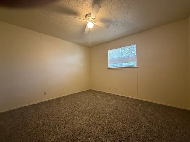 a view of an empty room and a chandelier fan
