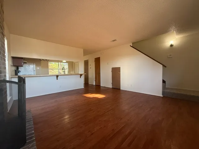 a view of a livingroom with wooden floor and kitchen space