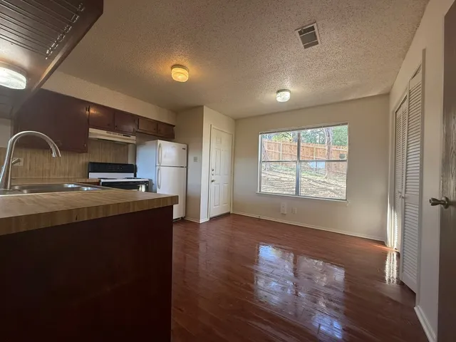 a view of a kitchen with a fridge and wooden floor