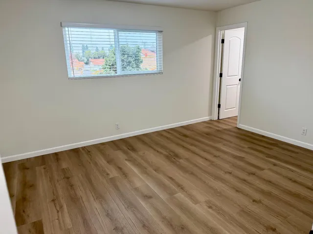 an empty room with wooden floor and window