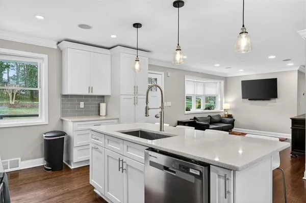 a kitchen with stainless steel appliances granite countertop a sink a center island and windows