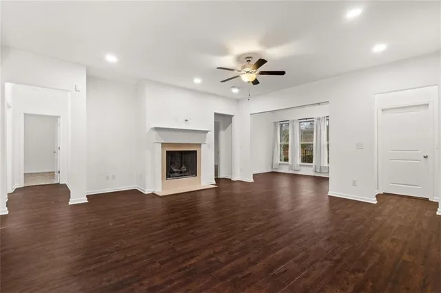 a view of an empty room with wooden floor and a fireplace