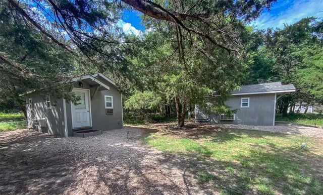 a dirt road with large trees and wooden fence