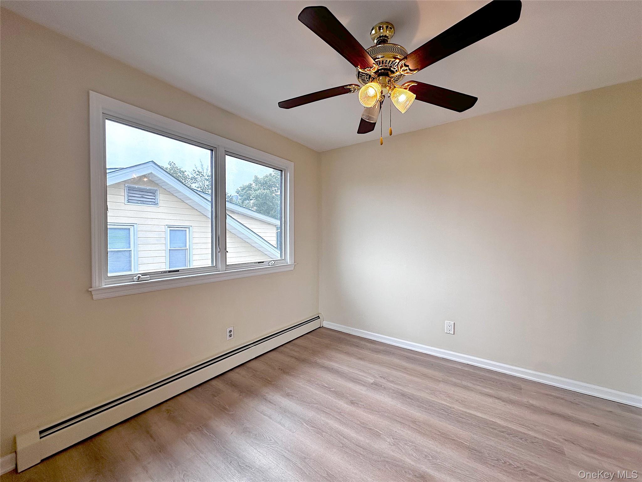 25 Acacia Terrace, Unit 2 New Rochelle, NY 10805 - Photo 9 of 28 an empty room with wooden floor fan and windows