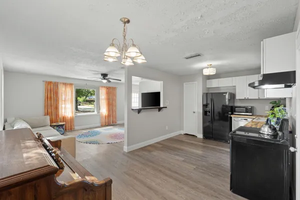 a open kitchen with a refrigerator a stove top oven a dining table and chairs