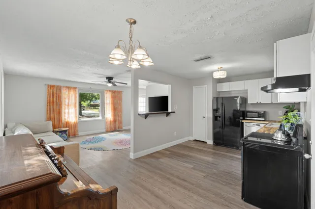 a open kitchen with a refrigerator a stove top oven a dining table and chairs