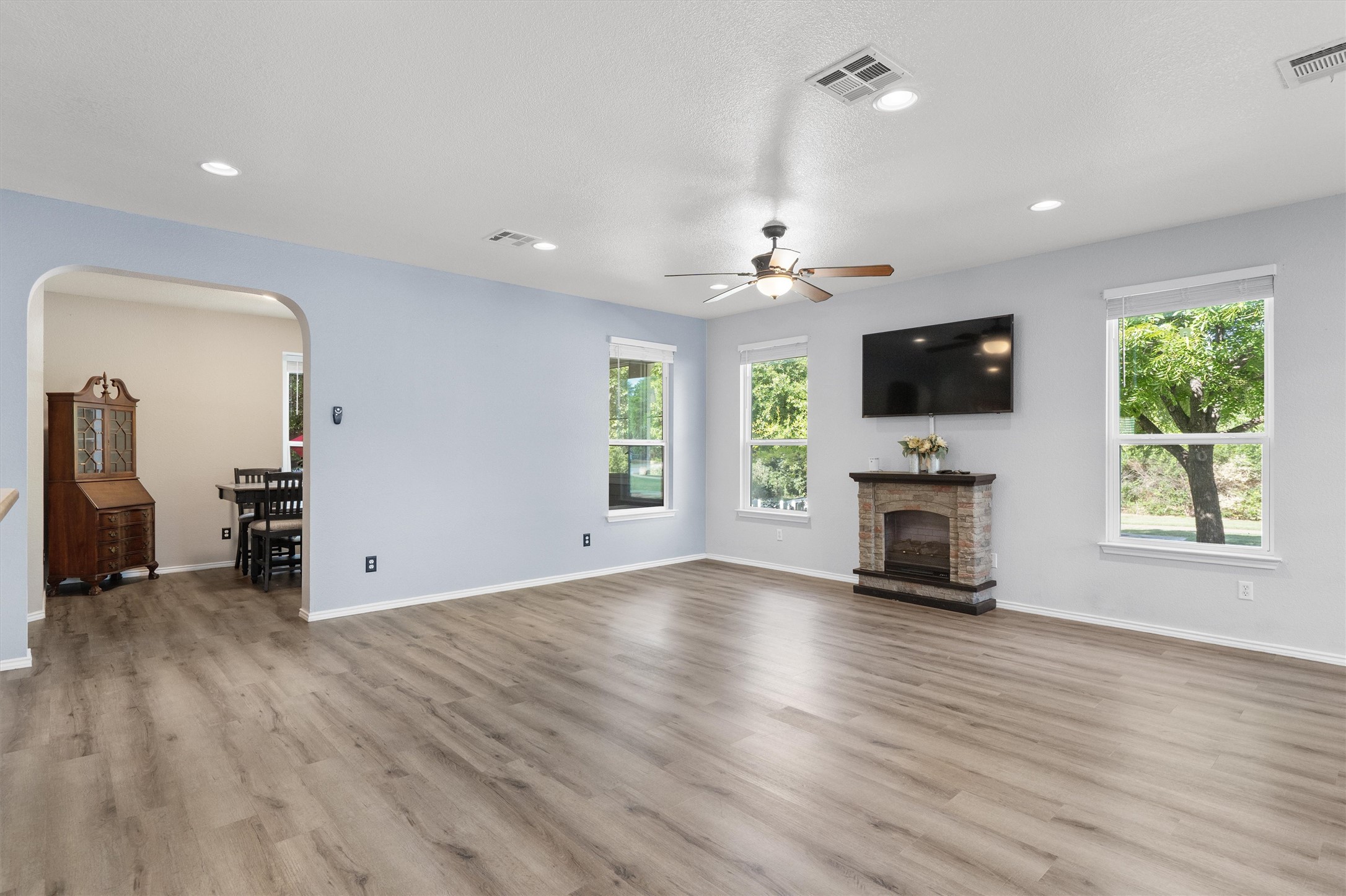 1833 Thompson Trail Round Rock, TX 78664 - Photo 6 of 40 A spacious common area boasts wood flooring, a fireplace, and an arched entry leading to an adjacent room.