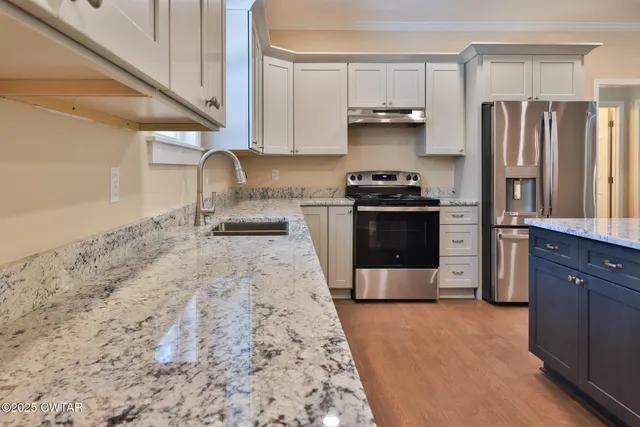 a kitchen with stainless steel appliances granite countertop a stove a refrigerator and a sink