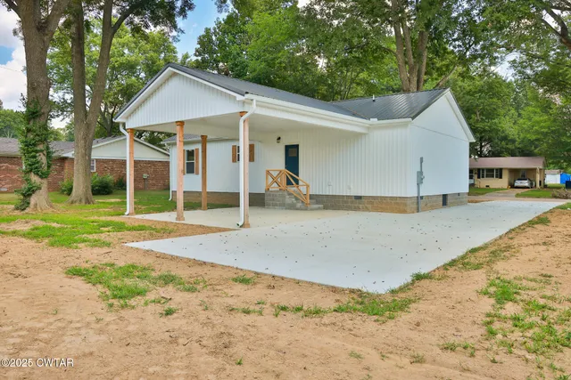 a view of a house with a yard and large tree
