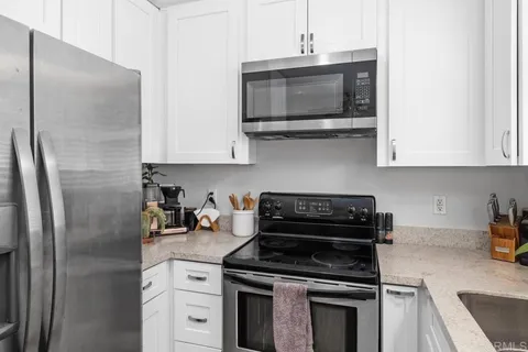 a kitchen with stainless steel appliances granite countertop a stove a microwave a refrigerator and cabinets