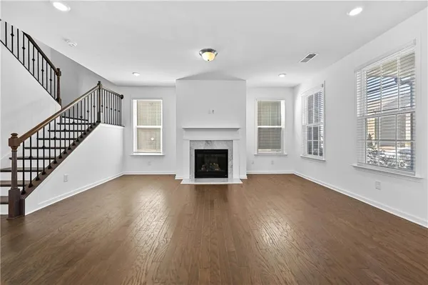 a view of an empty room with wooden floor fireplace and a window
