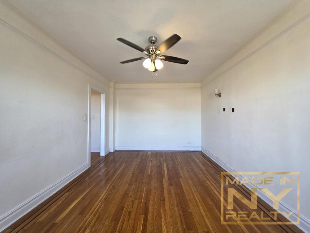 44-01 34th Avenue, Unit 4F Queens, NY 11101 - Photo 4 of 9 a view of a room with wooden floor and a ceiling fan