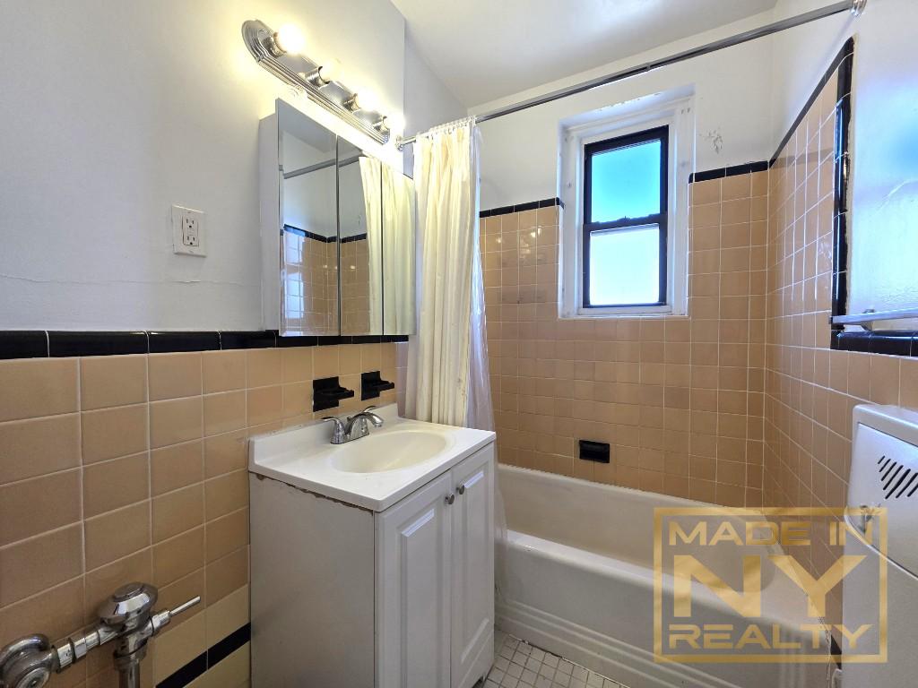44-01 34th Avenue, Unit 4F Queens, NY 11101 - Photo 5 of 9 a bathroom with a bathtub a sink and a mirror