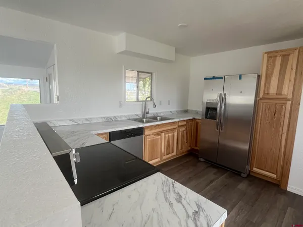 a kitchen with granite countertop a refrigerator a sink a stove a counter space and cabinets
