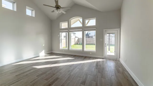 an empty room with wooden floor chandelier and windows