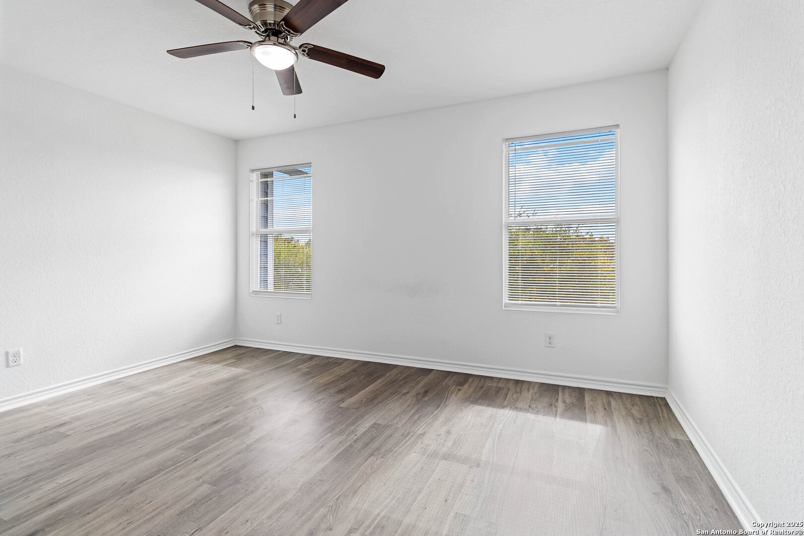 6942 Crestway Road San Antonio, TX 78239 - Photo 12 of 22 an empty room with wooden floor chandelier fan and windows