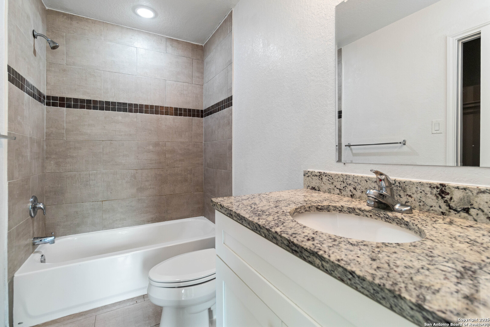 6942 Crestway Road San Antonio, TX 78239 - Photo 21 of 22 a bathroom with a granite countertop sink a toilet and shower