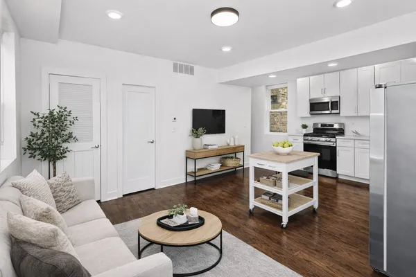 a living room with furniture kitchen view and a wooden floor