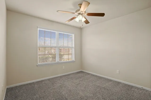 an empty room with a chandelier fan and windows