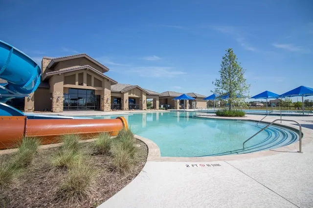 a view of a swimming pool with a bench and lawn chairs